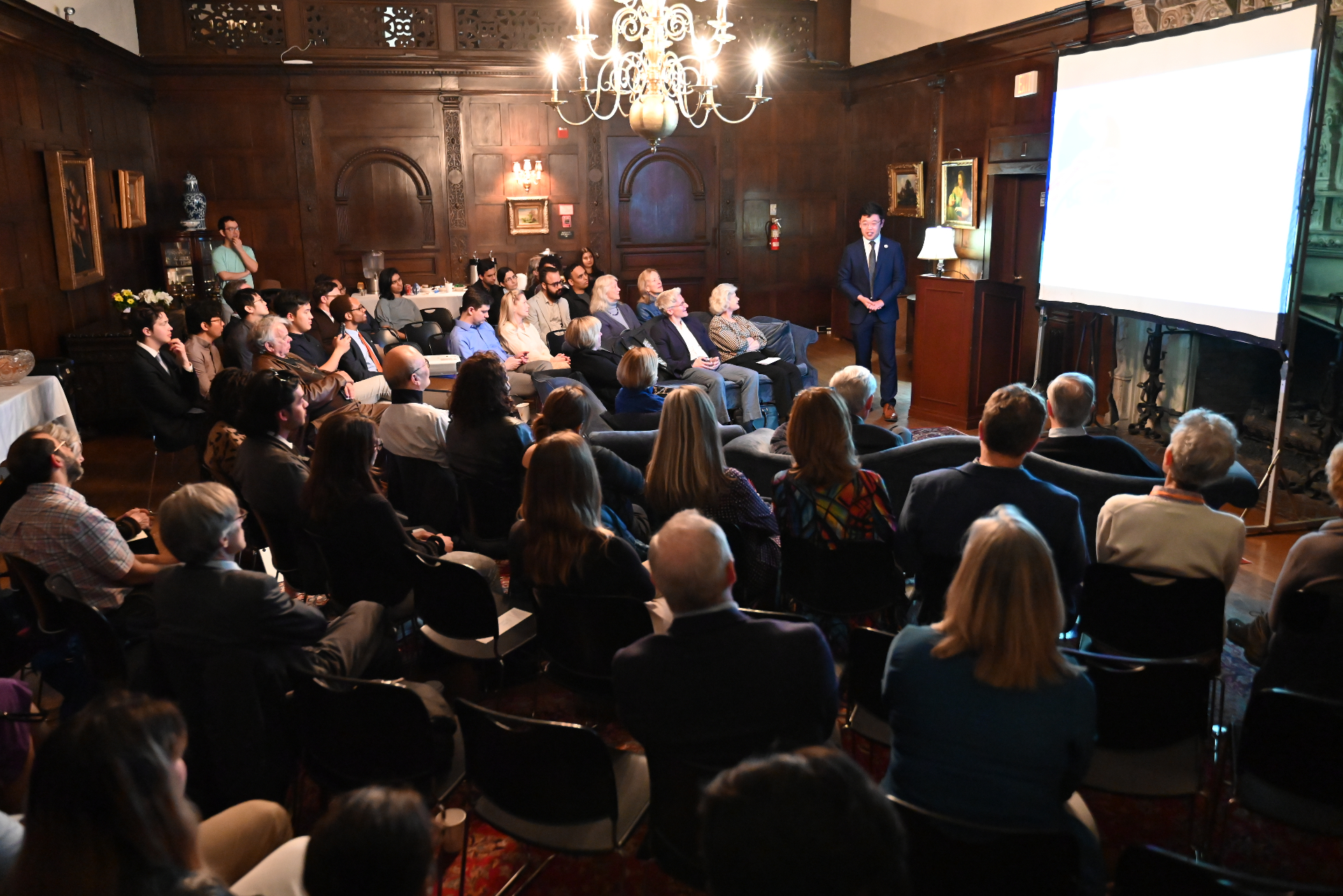 BCEA leadership addresses a packed audience at a Citizen Diplomacy evening in a wood-paneled hall