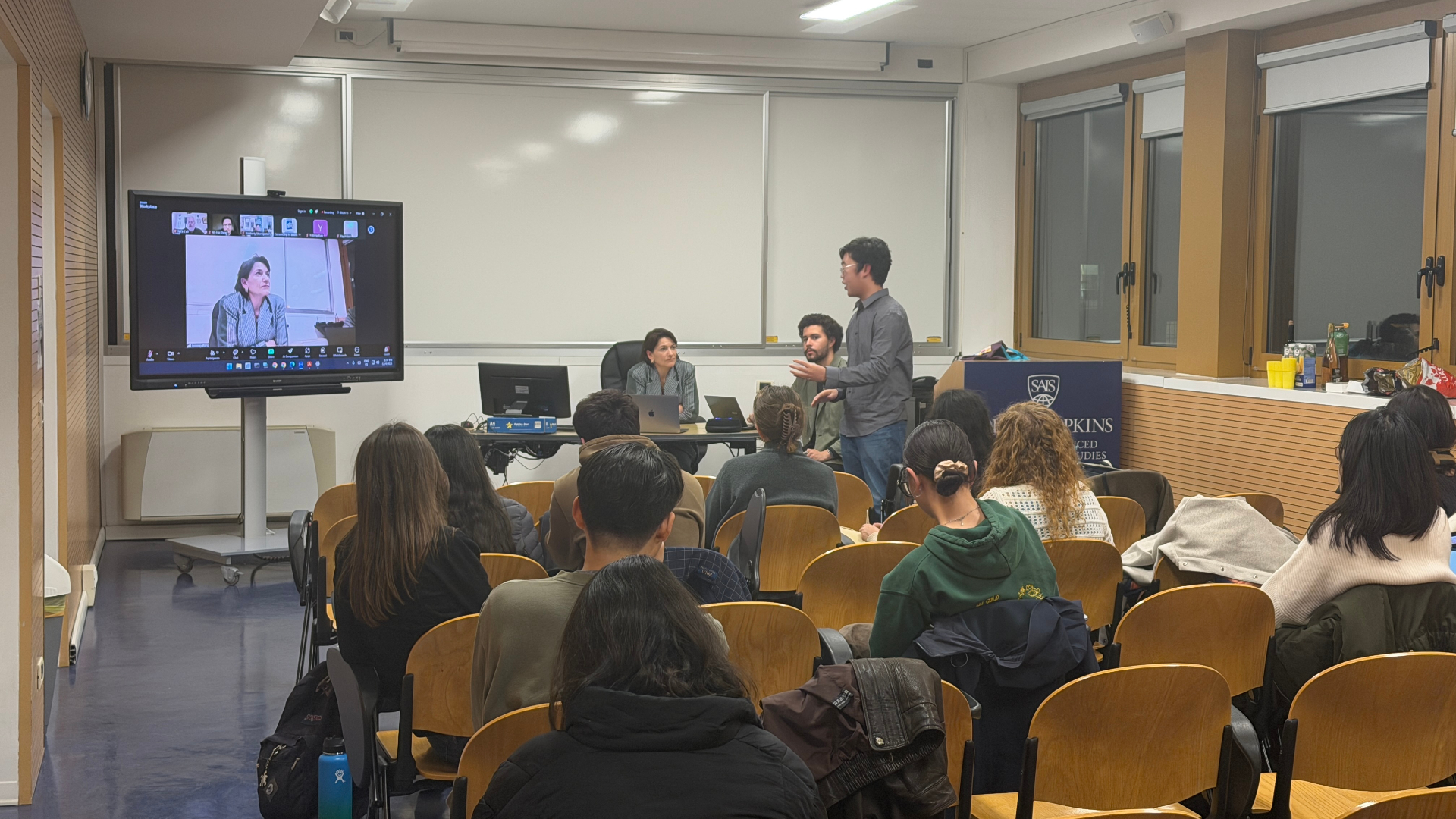 Student speaking during the Bologna summit, with panelists joining on screen.