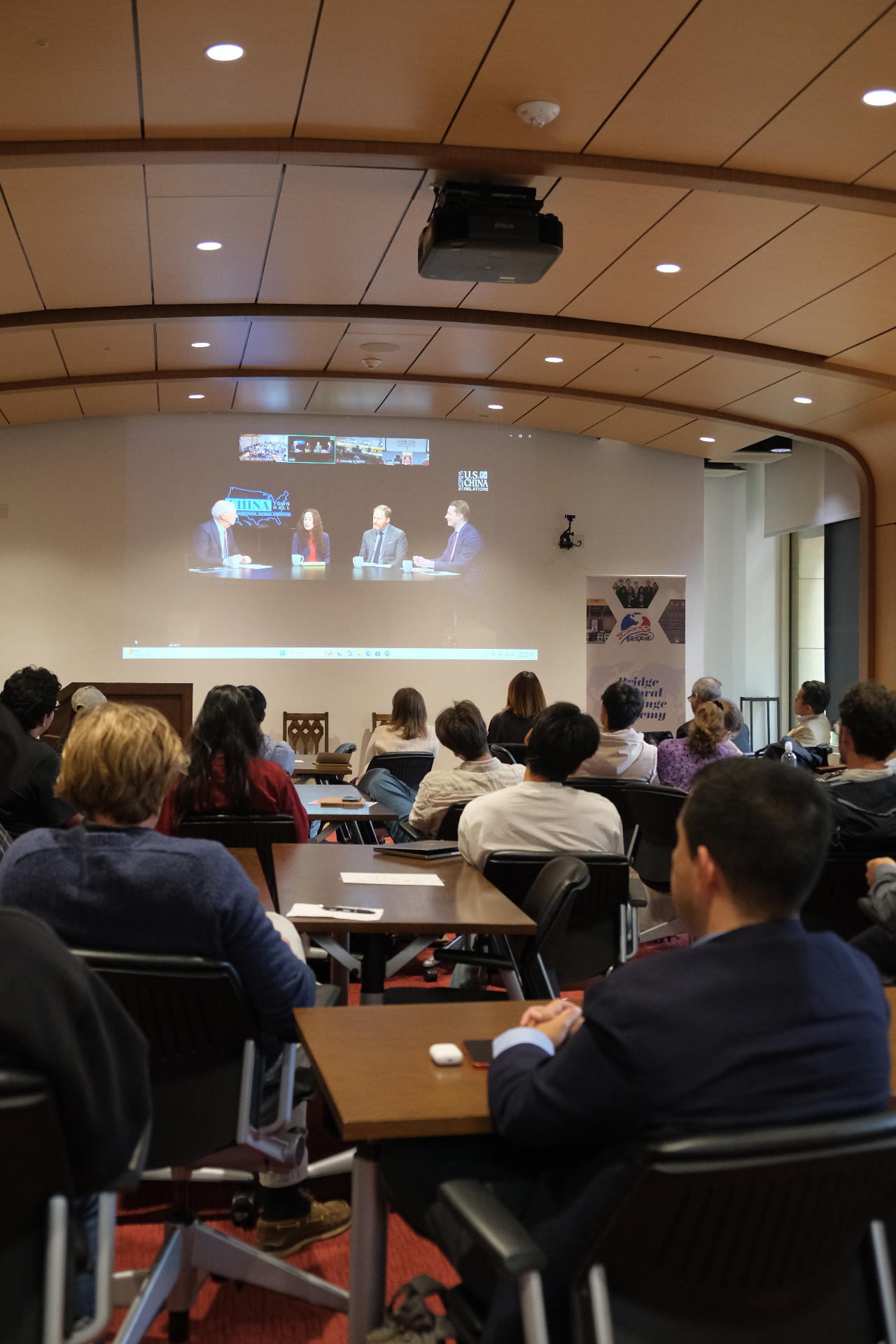 Attendees watch the China Town Hall national webcast in Los Angeles, with a BCEA banner beside the screen.